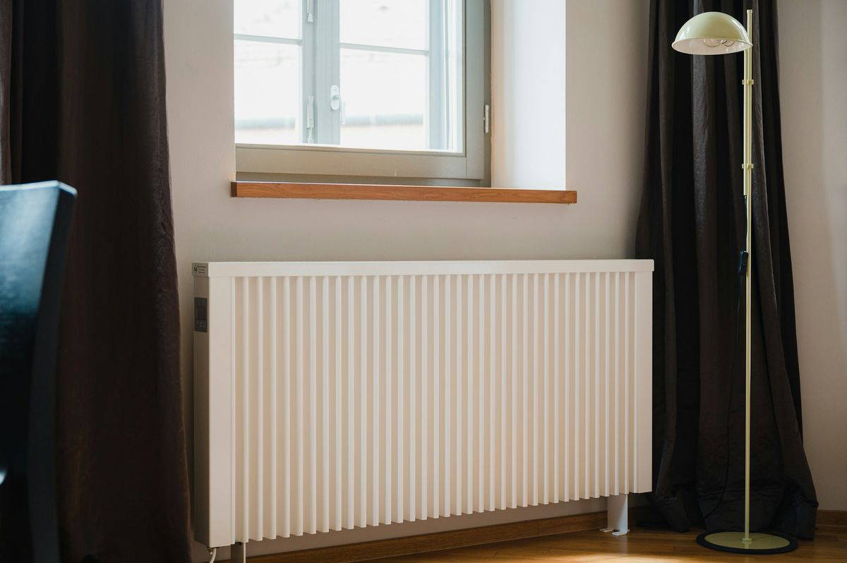 Een witte radiator onder een raam in een woonkamer